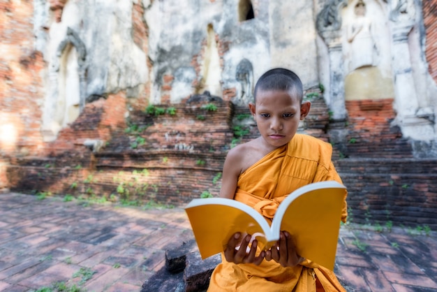 Anfängermönchlesung draußen, sitzend außerhalb des Klosters, Thailand