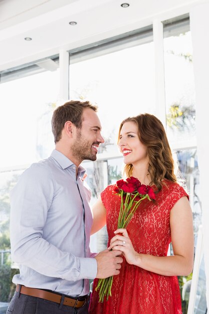 Angebotblumenblumenstrauß des jungen Mannes zur schönen Frau