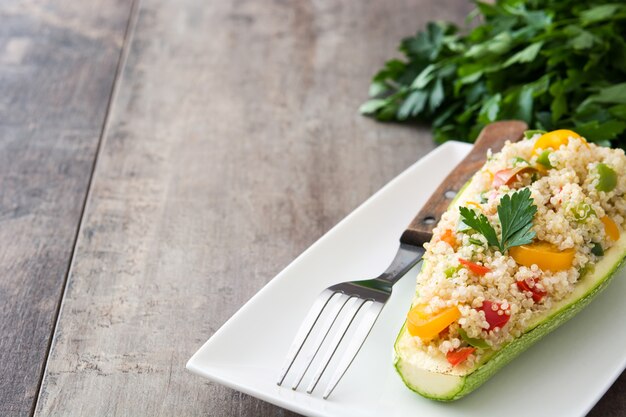 Angefüllte Zucchini mit Quinoa und Gemüse auf Holztischkopienraum