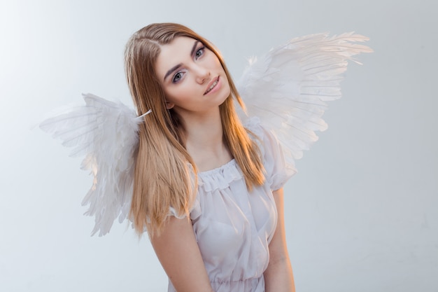 Foto un ángel del cielo joven, maravillosa chica rubia en la imagen de un ángel con alas blancas. primer plano del retrato