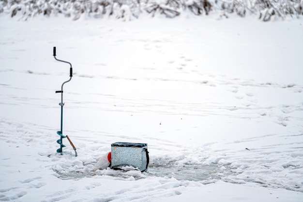 Angelausrüstung für das Eisfischen im Winter auf dem Hintergrund eines zugefrorenen Flusses