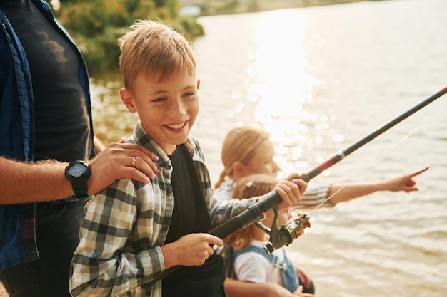 Angeln lernen Vater und Mutter mit Sohn und Tochter zusammen im Sommer im Freien