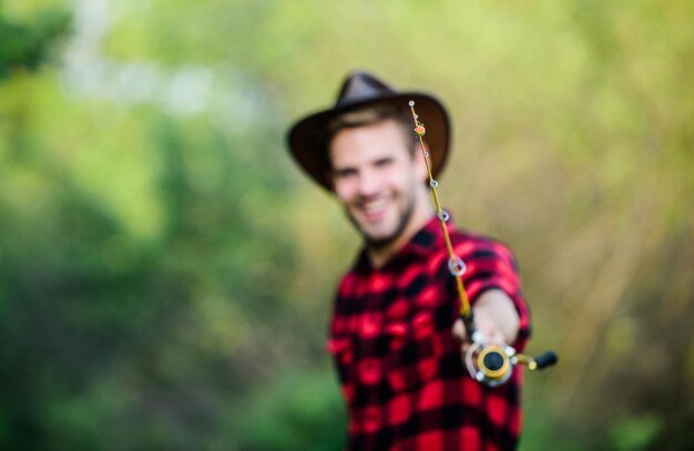 Angelrute selektiven Fokus glücklich Fischer in Hut verschwommen Western Portrait Vintage-Stil Mann Wilder Westen Retro-Cowboy Fliegenfischer Mann kariertes Hemd auf Ranch Fischer halten Fischnetz Hobby