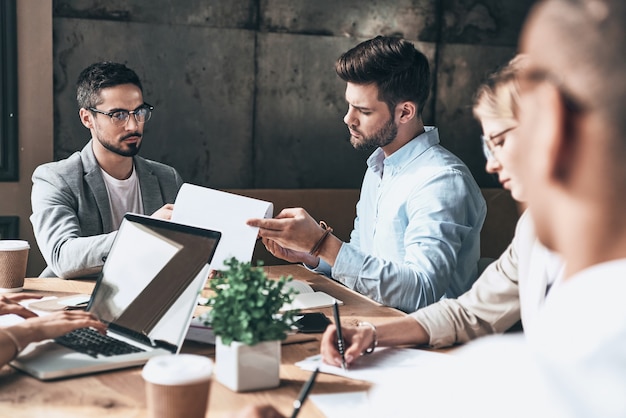 Angenehmer Arbeitstag. Gruppe junger moderner Menschen in intelligenter Freizeitkleidung, die über das Geschäft diskutieren