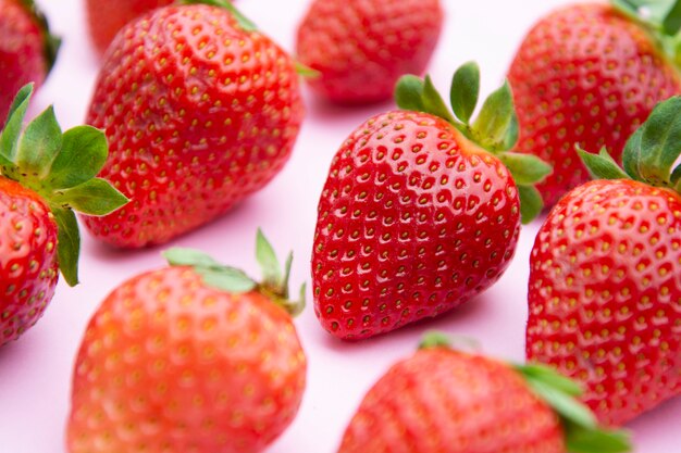 Angeredeter Erdbeerhintergrund. Frische Beeren des Sommers über rosa Brett.