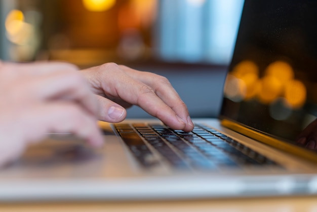 Angestellter, der auf Laptop mit bokeh schreibt