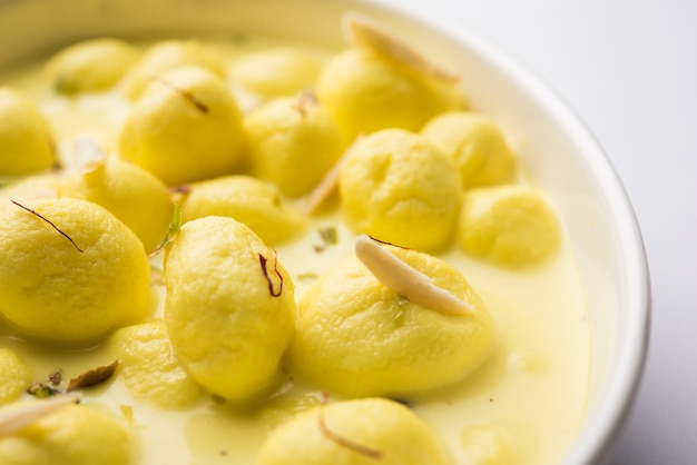 Angoori Rasmalai é uma sobremesa indiana doce com frutas secas e coberturas de açafrão, servida em uma tigela sobre um fundo melancólico. foco seletivo