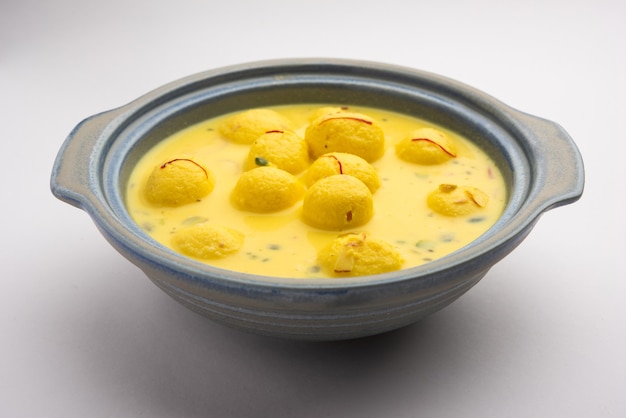 Angoori Rasmalai é uma sobremesa indiana doce com frutas secas e coberturas de açafrão, servida em uma tigela sobre um fundo temperamental. foco seletivo