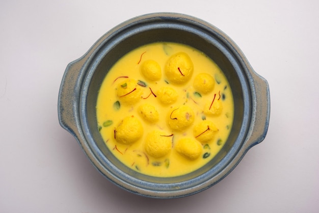 Angoori Rasmalai ist ein indisches Dessert mit Trockenfrüchten und Safran-Toppings, das in einer Schüssel auf stimmungsvollem Hintergrund serviert wird. selektiver Fokus