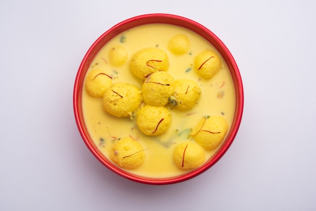 Angoori Rasmalai ist ein indisches Dessert mit Trockenfrüchten und Safran-Toppings, das in einer Schüssel auf stimmungsvollem Hintergrund serviert wird. selektiver Fokus