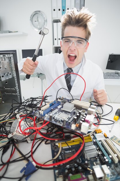 Angry computer engineer segurando martelo sobre o console