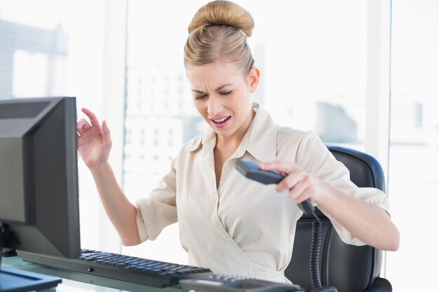 Angry joven rubia empresaria colgando el teléfono