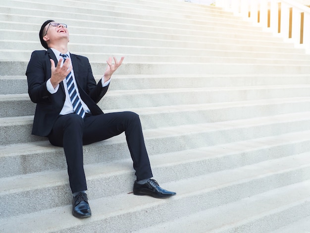 Angry strain happy businessman está sentado en las escaleras