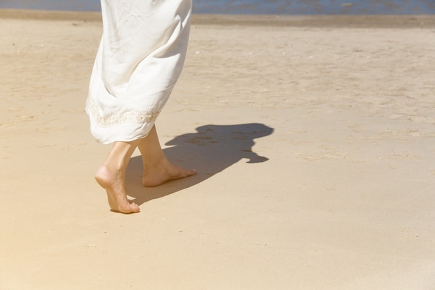 Ângulo baixo atrás de uma mulher caminhando descalça na praia