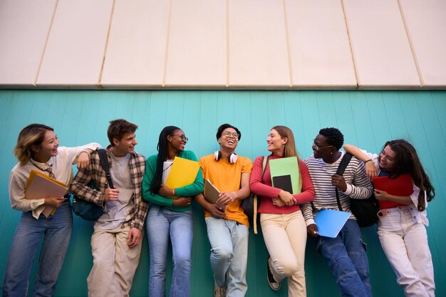 Ángulo bajo gran grupo multiétnico y diversos estudiantes sonriendo mirándose unos a otros