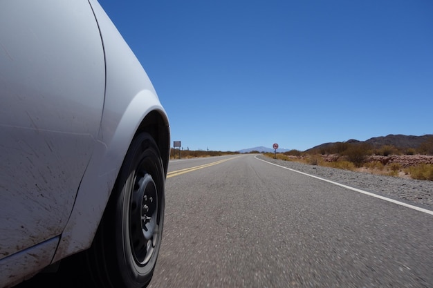 ángulo bajo de una rueda de camión en un viaje por carretera a la carretera asfaltada en un paisaje desértico