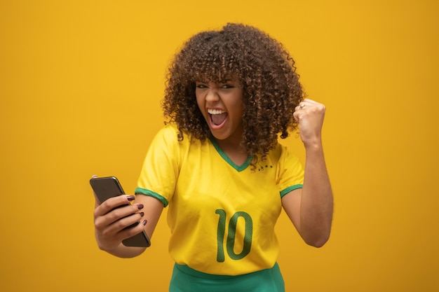 Anhänger der brasilianischen Fußballmannschaft, die ein Tor feiert, indem sie das Smartphone aufpasst