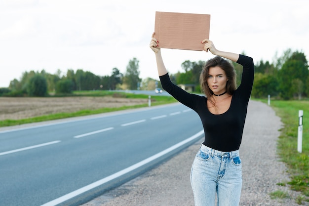 Anhalter auf der Straße hält ein leeres Pappschild