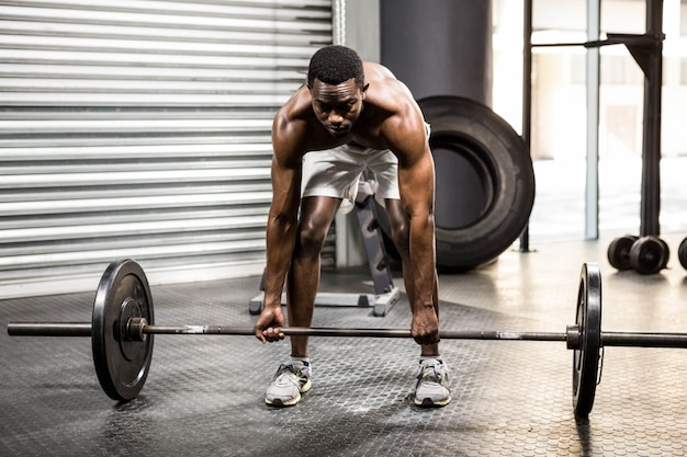 Anhebender Barbell des hemdlosen Mannes an der crossfit Turnhalle