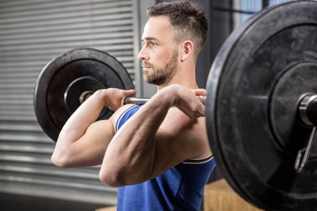 Anhebender Barbell des muskulösen Mannes an der crossfit Turnhalle