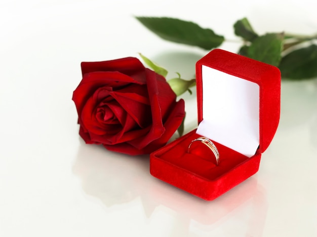 Foto un anillo de bodas en una caja roja abierta, junto a una rosa escarlata.