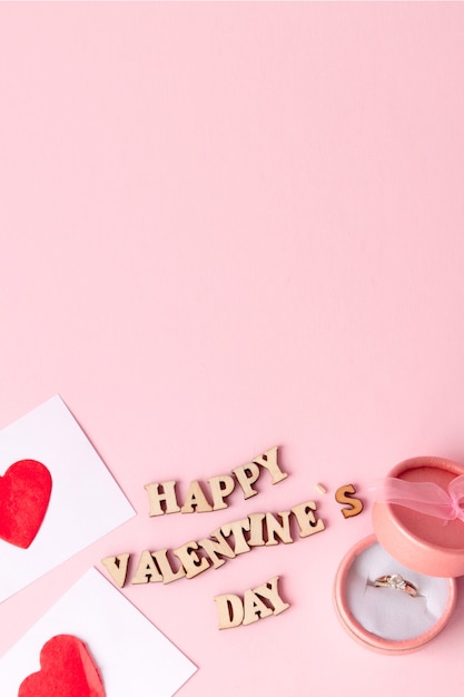 Anillo de bodas y muchos corazones con una inscripción Feliz día de San Valentín sobre un fondo rosa