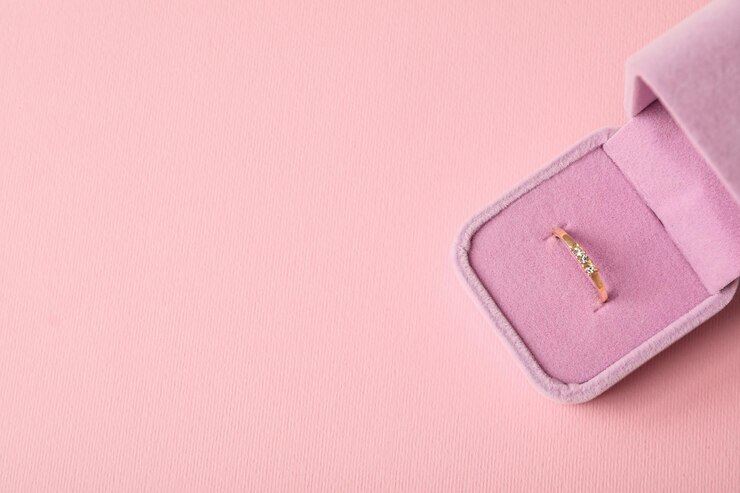 Anillo de bodas de oro en caso de espacio de fondo rosa para texto