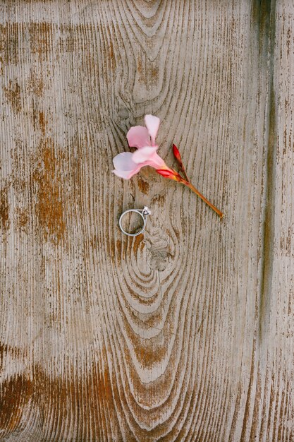 Anillo de compromiso de boda para la novia con una flor rosa sobre una textura de madera