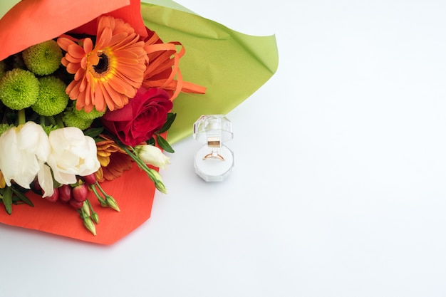 Anillo de compromiso en una caja de regalo con brillante ramo de flores. La oferta de casarse. Regalo para el día de San Valentín. Propuesta de matrimonio para mujer amada. Símbolo de amor y matrimonio.