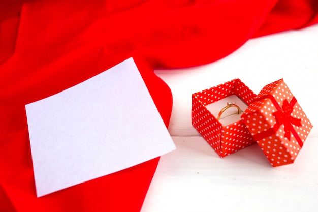 Anillo de compromiso en una caja roja sobre un fondo blanco de madera. Declaración de amor en el día de San Valentín