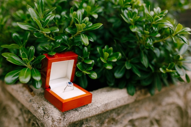 Un anillo de compromiso con una gema azul en una caja.