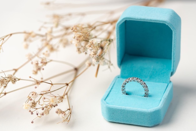 Anillo de diamantes dorados en la caja con fondo de flores blancas