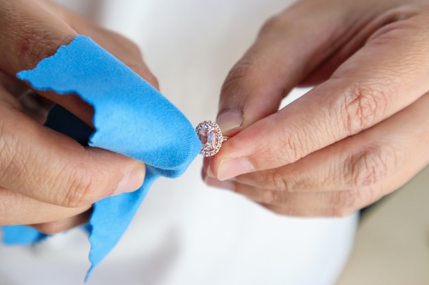 Foto anillo de diamantes de joyería de pulido y limpieza a mano de joyero con tejido de microfibra