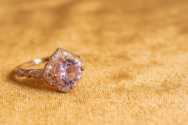 Anillo de diamantes de joyería rosa sobre fondo de tela dorada de cerca