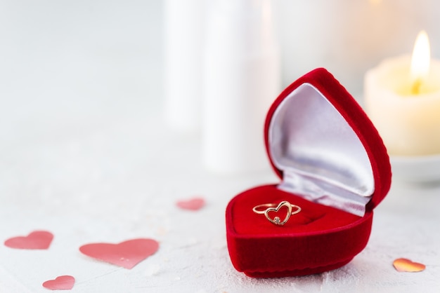 Anillo en forma de corazón en una caja de regalo en el fondo de productos de spa.