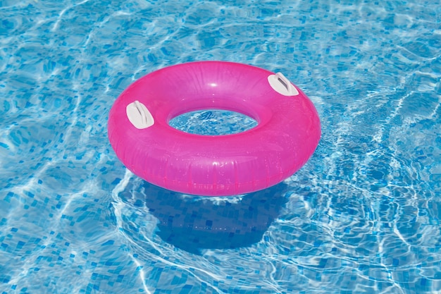 Anillo inflable rosa flotando en la piscina Ondas de agua azul claro