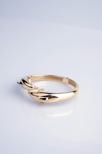 un anillo de oro con una flor en él se sienta en una superficie blanca