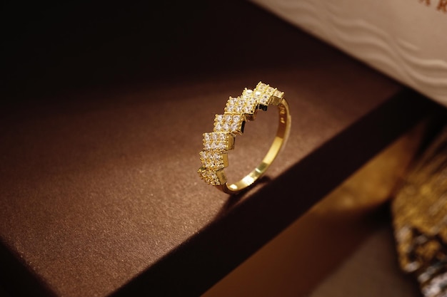 Anillo de oro lindo con diamantes, zirconia cúbica, esmeraldas y piedras preciosas sobre fondo marrón