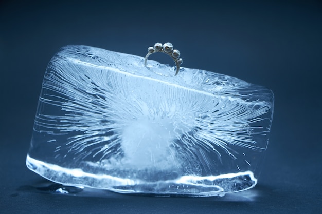 Foto anillo de plata congelado en un trozo de hielo.