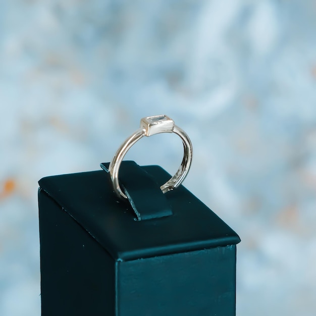 un anillo se sienta en una caja con un fondo azul.