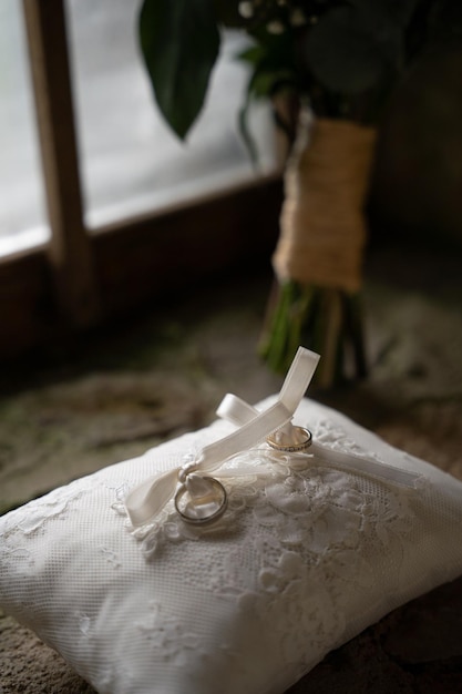 anillos de boda en una almohada, un ramo de flores en el fondo y una ventana, joyas