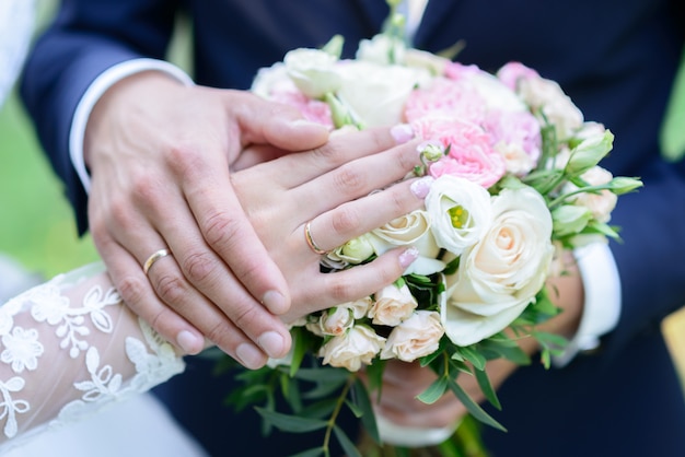 Anillos de boda en una almohada un ramo de peonías manos de boda con anillos