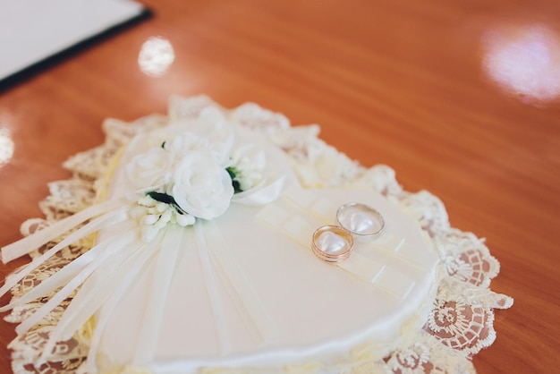 Anillos de boda en una almohada de raso blanco