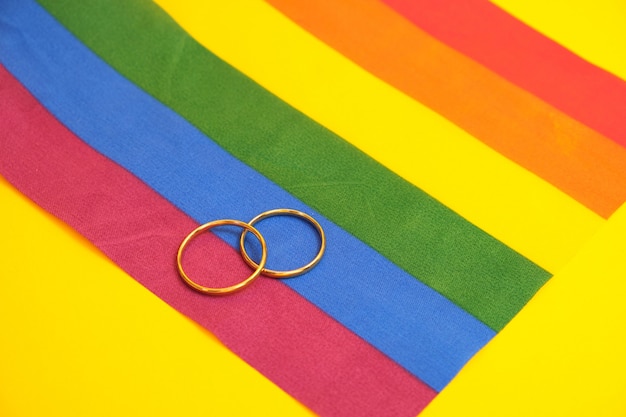 Anillos de boda en bandera lgbt, fondo amarillo, espacio de copia