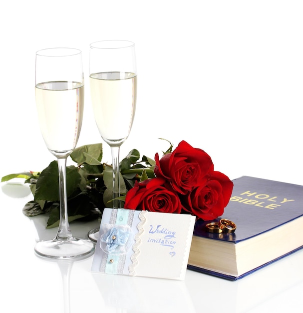 Anillos de boda en la Biblia con rosas y copas de champán aislado en blanco