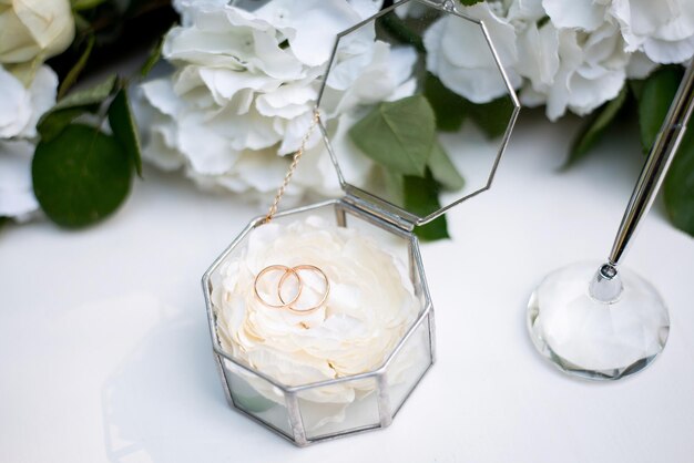 Anillos de boda en una caja de cristal sobre una mesa blanca