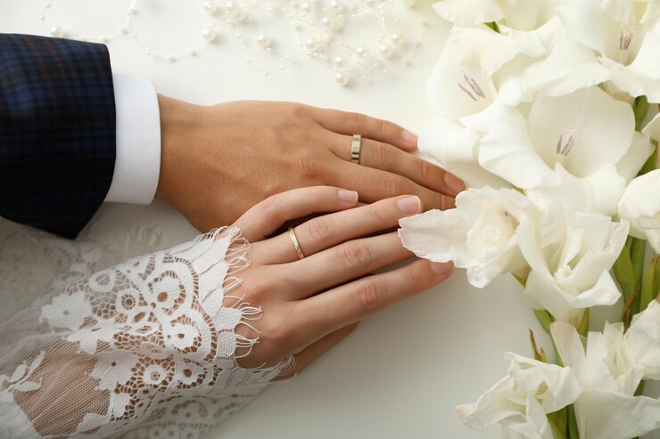 Anillos de boda dorados en manos de los recién casados sobre un fondo claro
