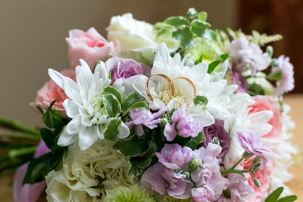 Los anillos de boda se encuentran en los pétalos de un ramo de flores de novia.