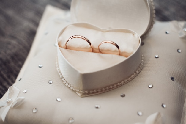 Los anillos de boda están en una caja con forma de corazón.