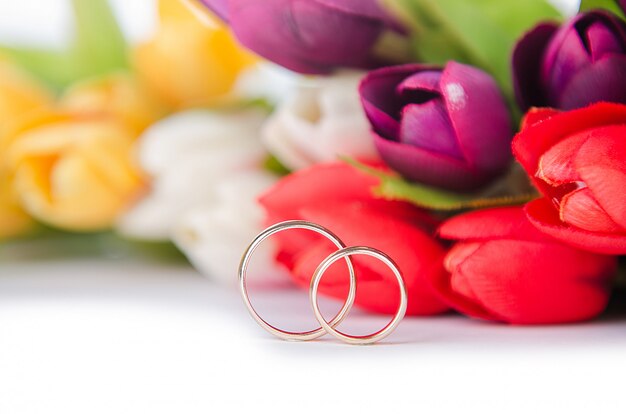 Anillos de boda y flores aisladas sobre fondo blanco